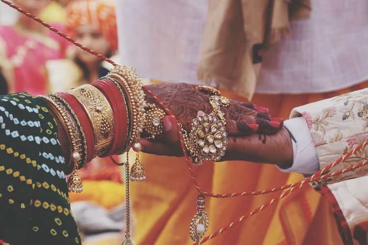 Cropped image of bride and groom holding hands during wedding ceremony