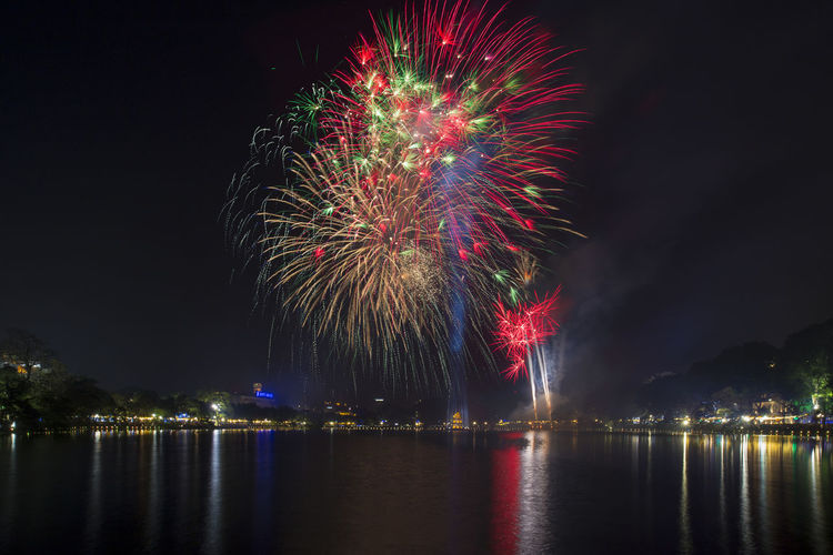 Scenic view of lake against firework display at night