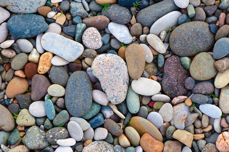 Bright background of multi-colored round stones, sea pebbles close up.