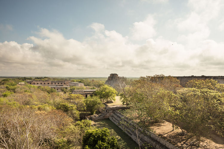 High angle view of old ruins in forest against cloudy sky