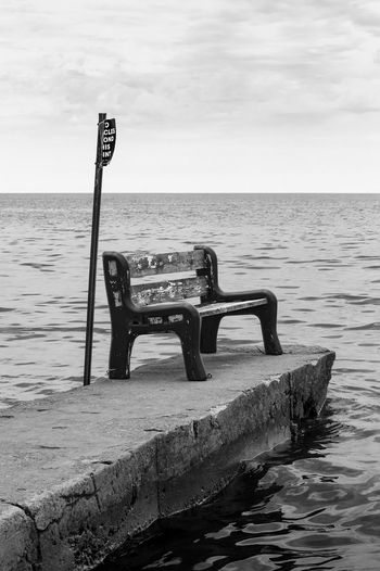 A empty abandoned park bench and sign on a broken pier one morning turkey point, lake erie, ontario.