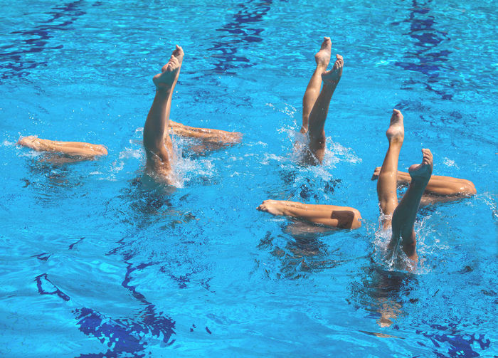 Low section of young women with feet up in swimming in pool
