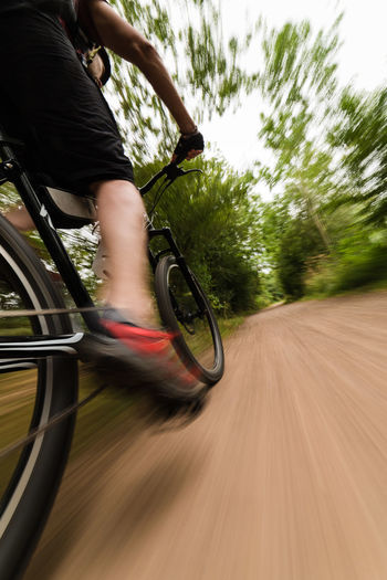 Low section of man riding bicycle on road