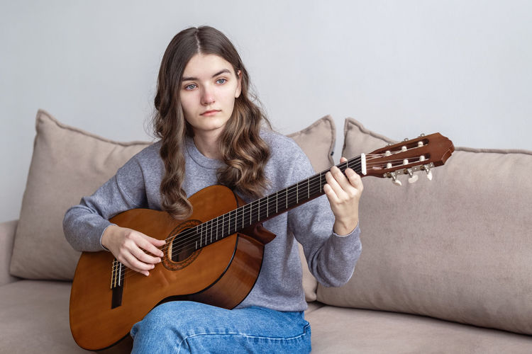 Sad girl playing guitar at home