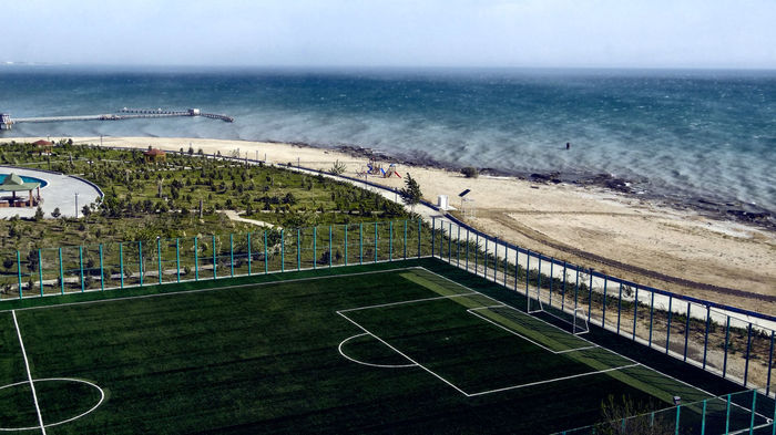 High angle view of soccer field by sea against sky