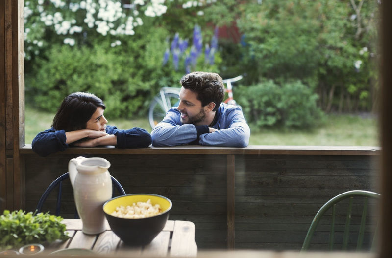 Loving couple looking at each while leaning on log cabin