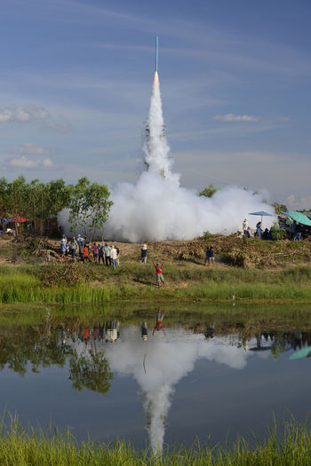 Group of people watching rocket launch on landscape