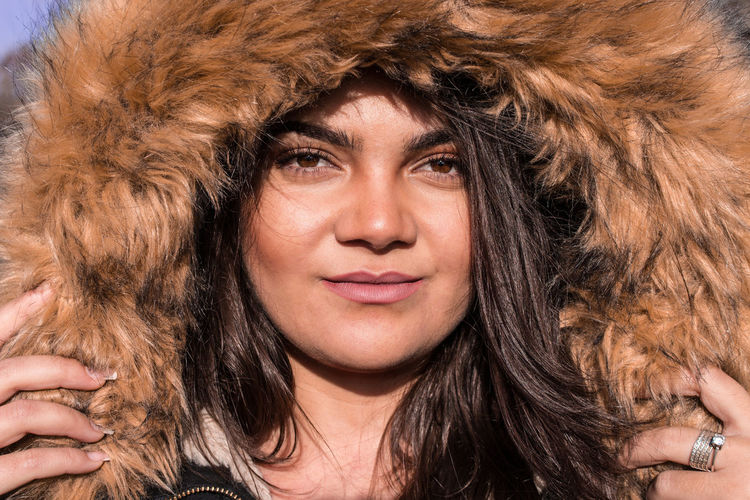 Close-up portrait of young woman wearing fur coat