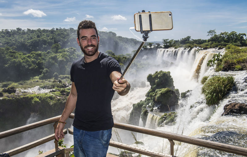 Man taking a selfie with monopod at iguazu waterfalls in argentina