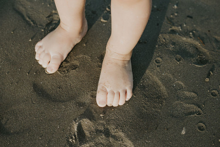 Low section of child legs on sand