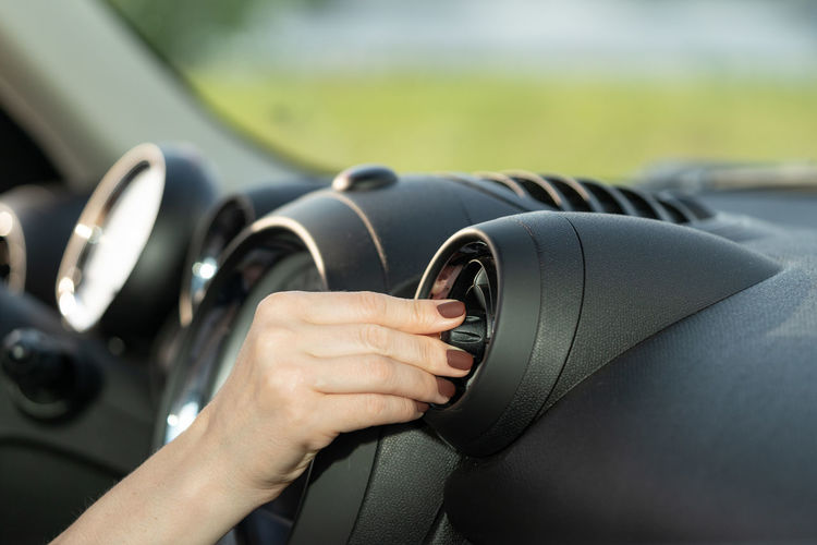 Cropped hand adjusting air conditioner in car