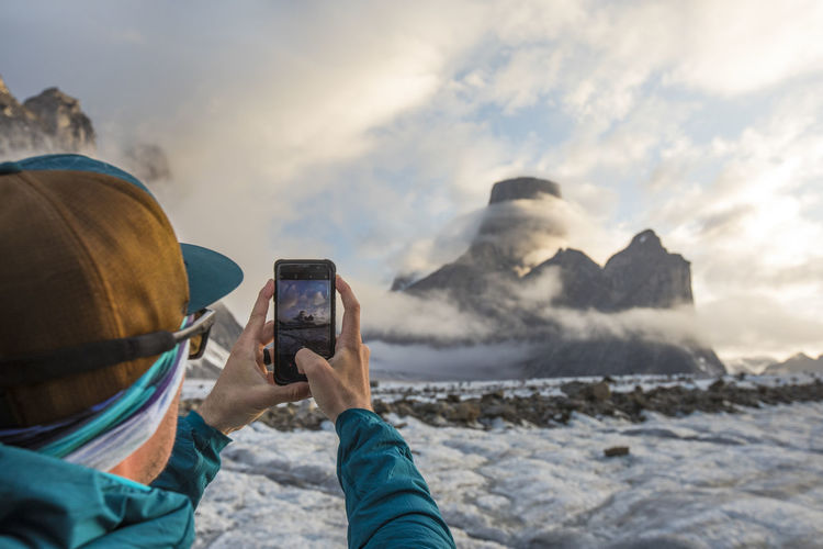 Man uses smartphone to take a photo of mount asgard.