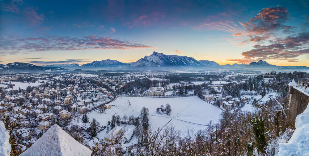Scenic view of snow covered town against sky during sunset