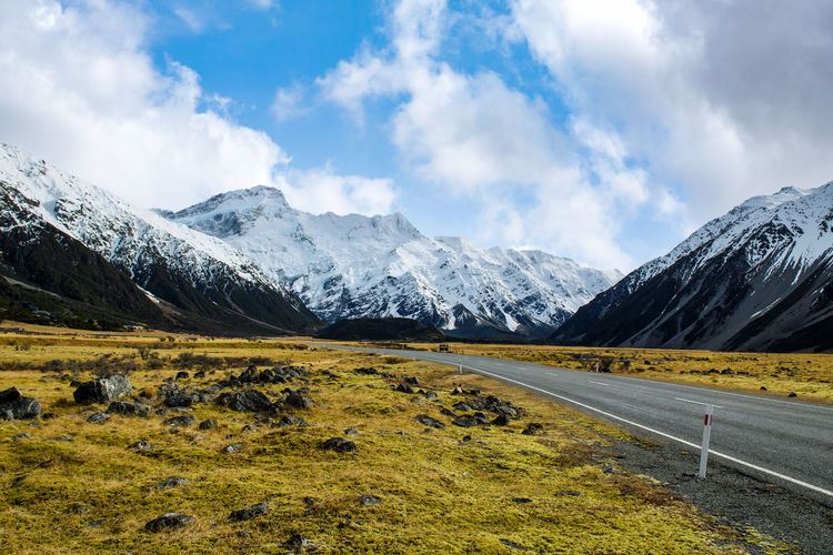 On the asphalt road to the big and tall mountains in winter, blue skies in new zealand