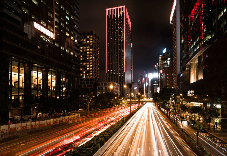 Light trails on city street amidst buildings at night
