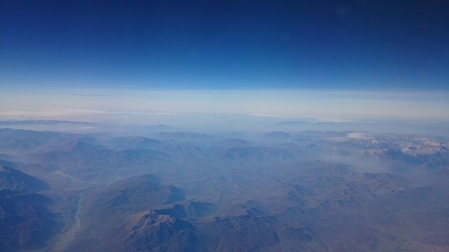Aerial view of mountains against blue sky