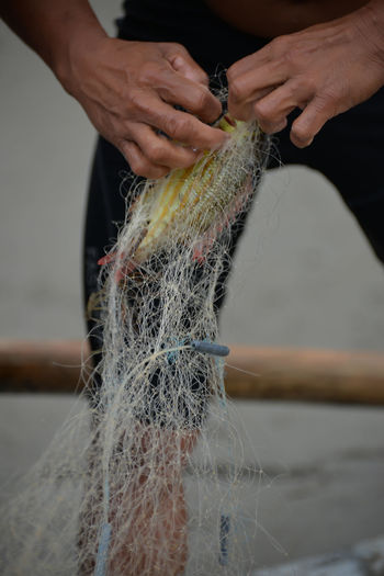 Close-up of man working on fishing net