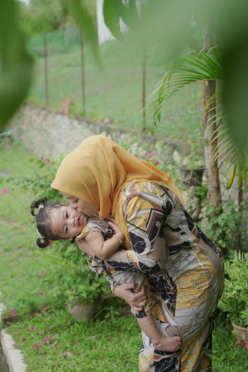 Full length portrait of young woman carrying baby