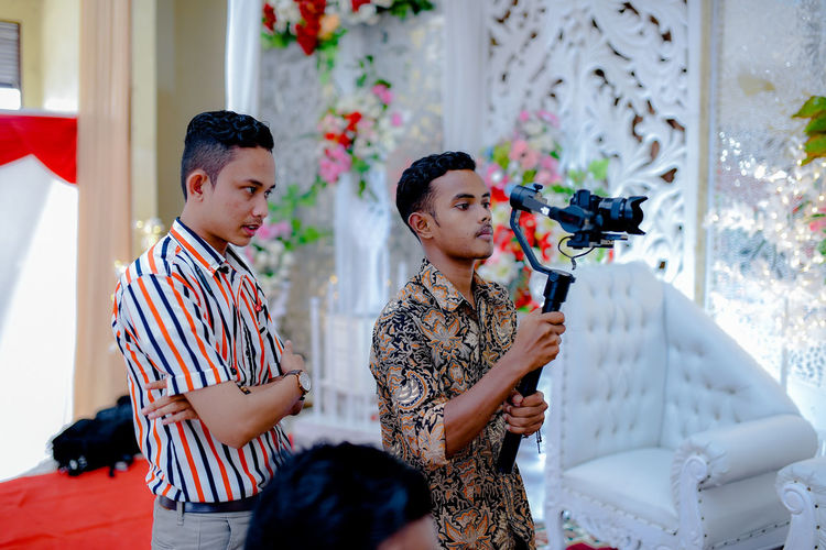 Man looking at friend filming in wedding ceremony