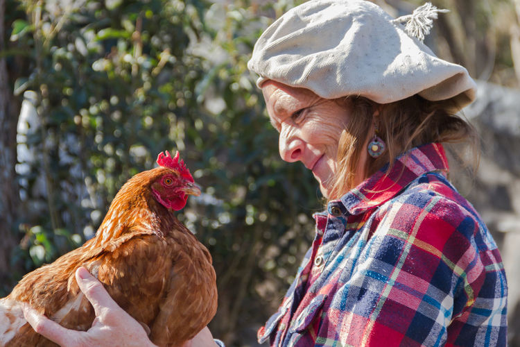 Mature woman with hen at farm
