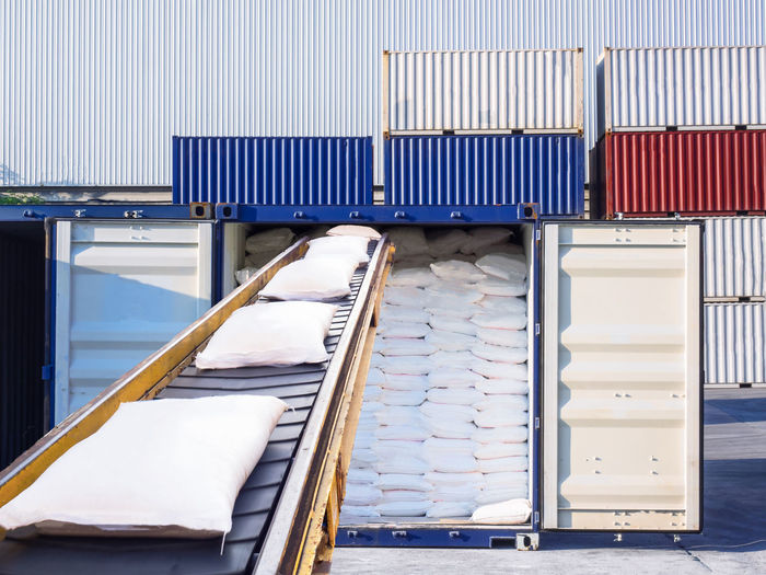 Sacks on conveyor belt against cargo containers