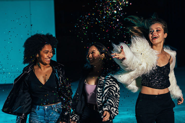 Young smiling women throwing confetti on stage
