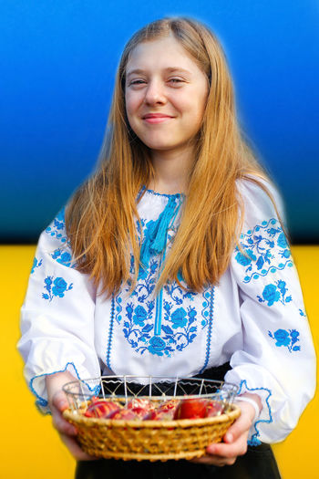 Portrait of smiling young woman standing against blue background