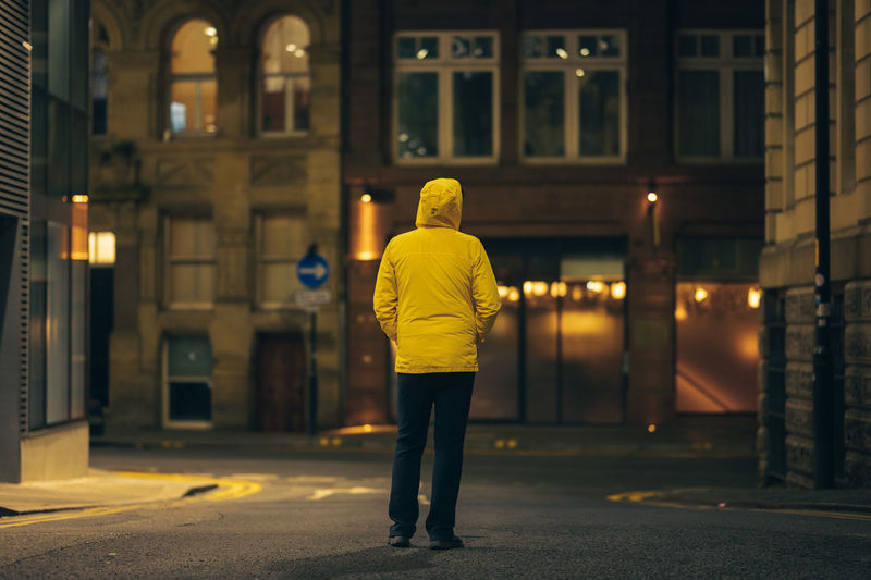 Rear view of man standing on street at night
