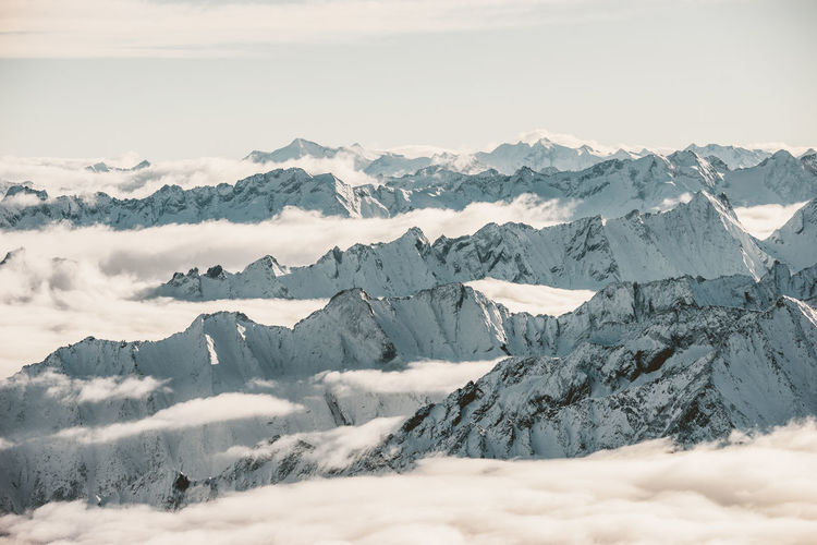 Layers of snow covered mountains above the clouds in tyrol, austria