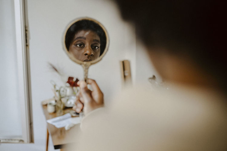 Young woman looking in mirror at home