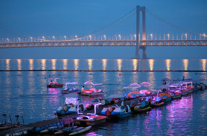 Pedal boats moored on pier against bay bridge at xinghai bay