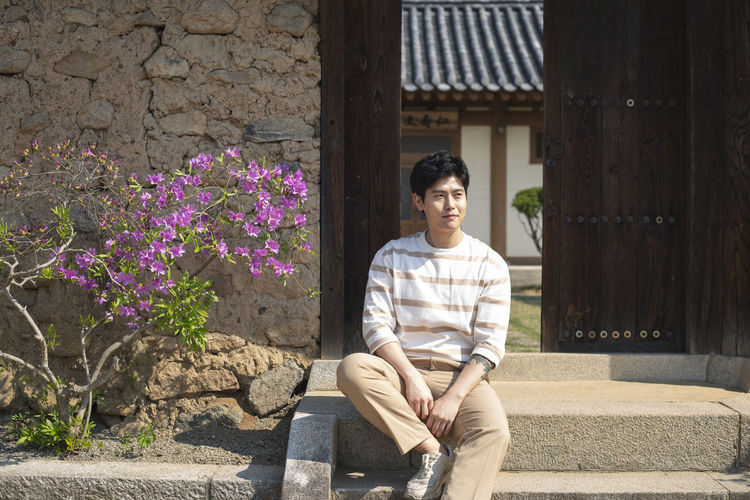 Full length of young man sitting outdoors