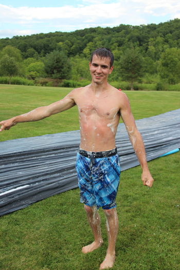 Young man standing against water slide on field