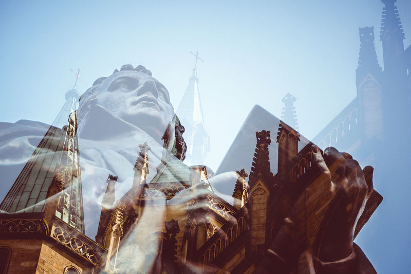 Double exposure of statue and church against sky