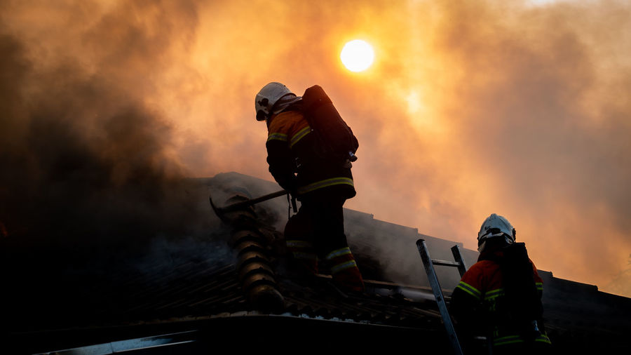 Firefighter working in roof in sunset