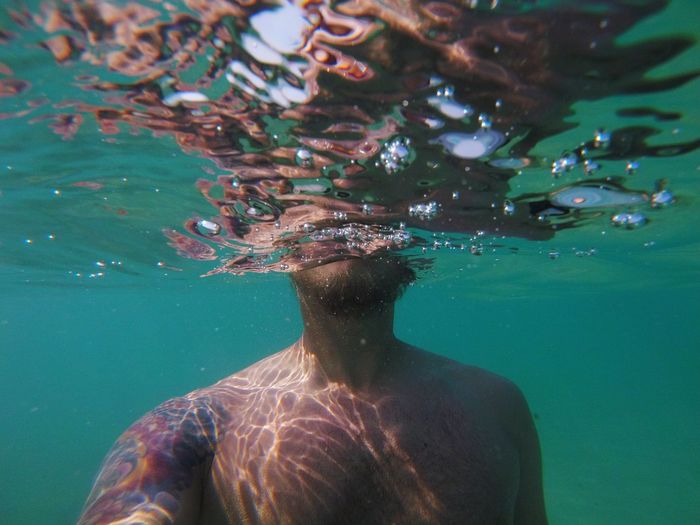 Rear view of shirtless man swimming in sea
