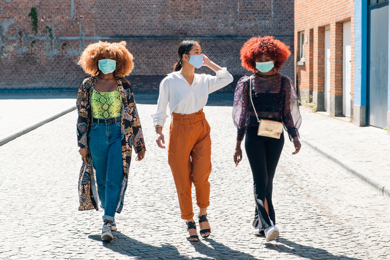 Female people walking in the street with protective mask - friends with surgical mask protection