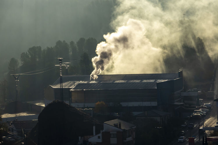 Smoke emitting from factory against sky