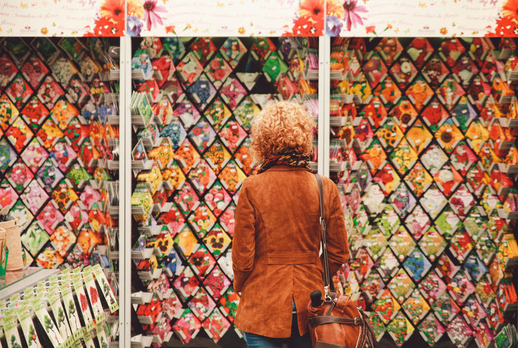 Rear view of woman looking at flower seed packets at market