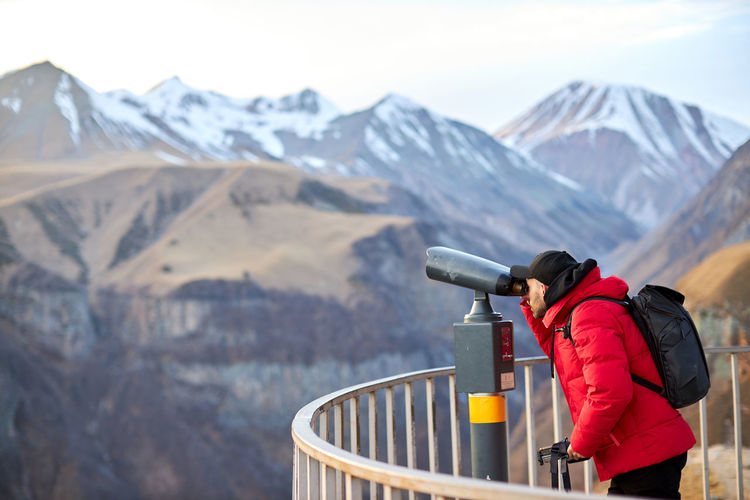 Man with black backpack looking on observation deck, tourist traveler on background panoramic