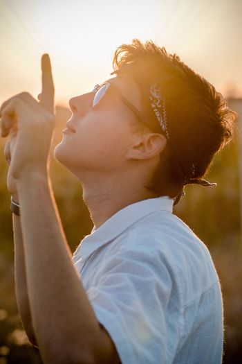 Side view of teenage boy wearing sunglasses while gesturing outdoors