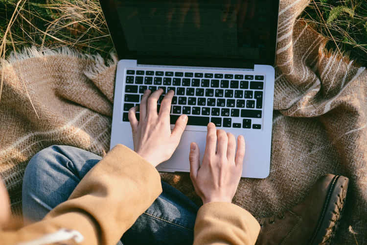 Cropped hands of person using laptop outdoors