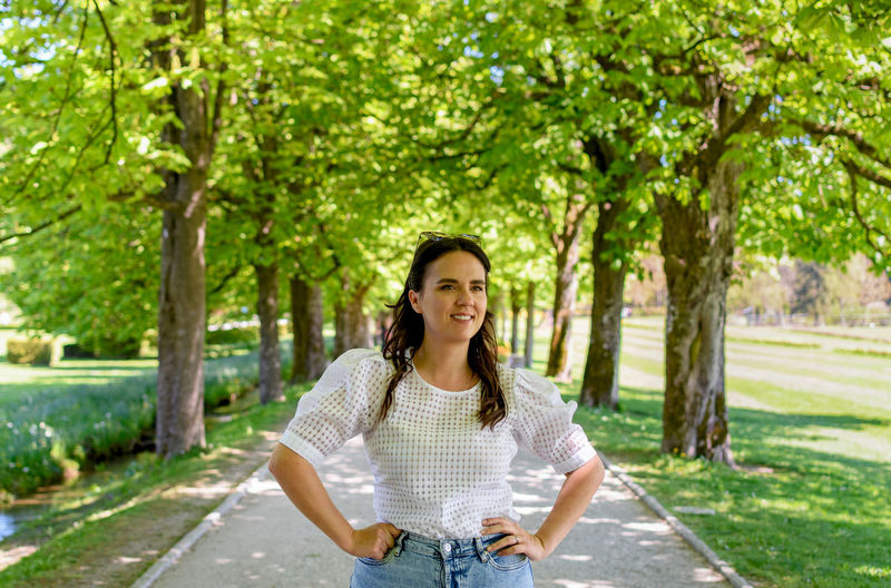 Portrait of beautiful young woman standing on path in park during spring.