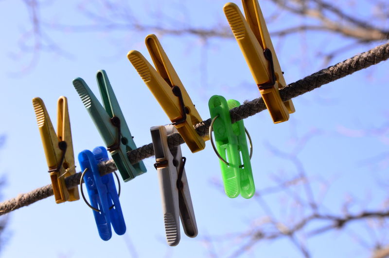 Low angle view of clothespins on clothesline against sky