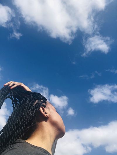 Low angle portrait of woman against blue sky