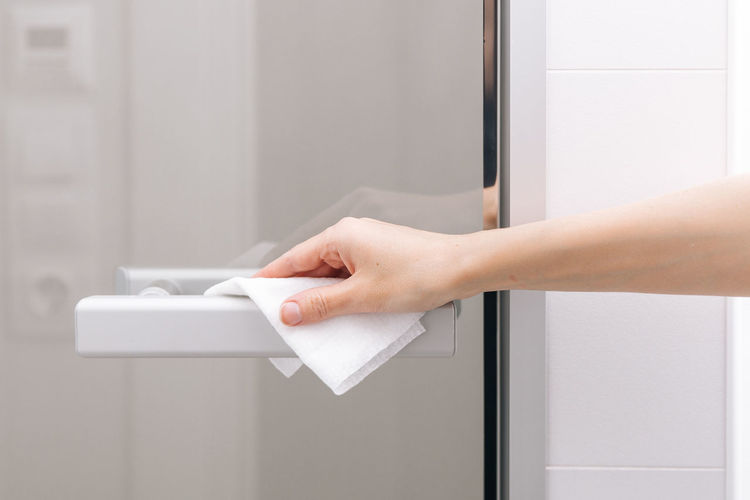 Cleaning glass door handles with an antiseptic wet wipe. woman hand using towel for cleaning