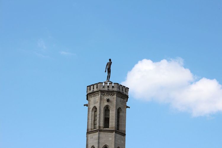 Low angle view of statue against historic building against sky