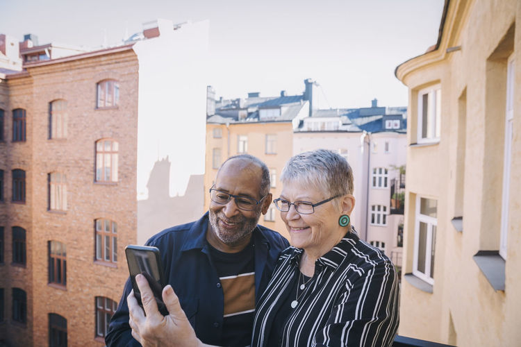 Senior couple taking selfie through mobile phone in balcony