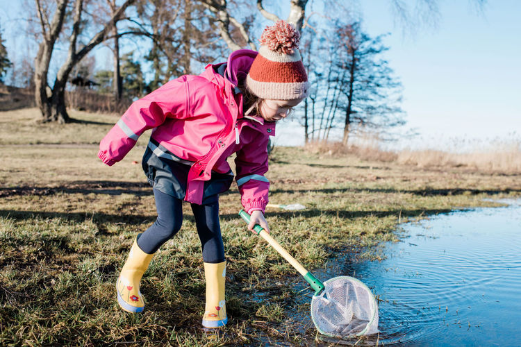 Young girl playing with a fishing net in the sea on a sunny winter day