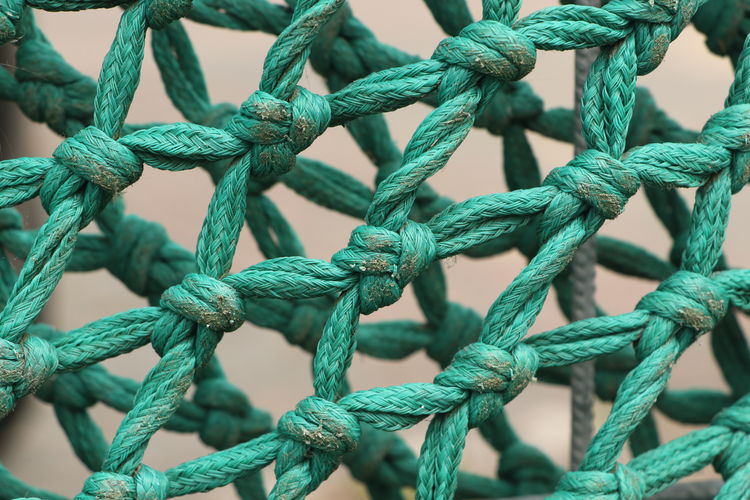 Knots in turquoise colored fishing net rope close up